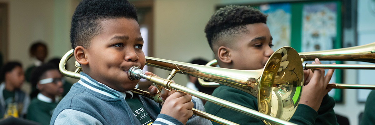 Two male students playing trombones in band class